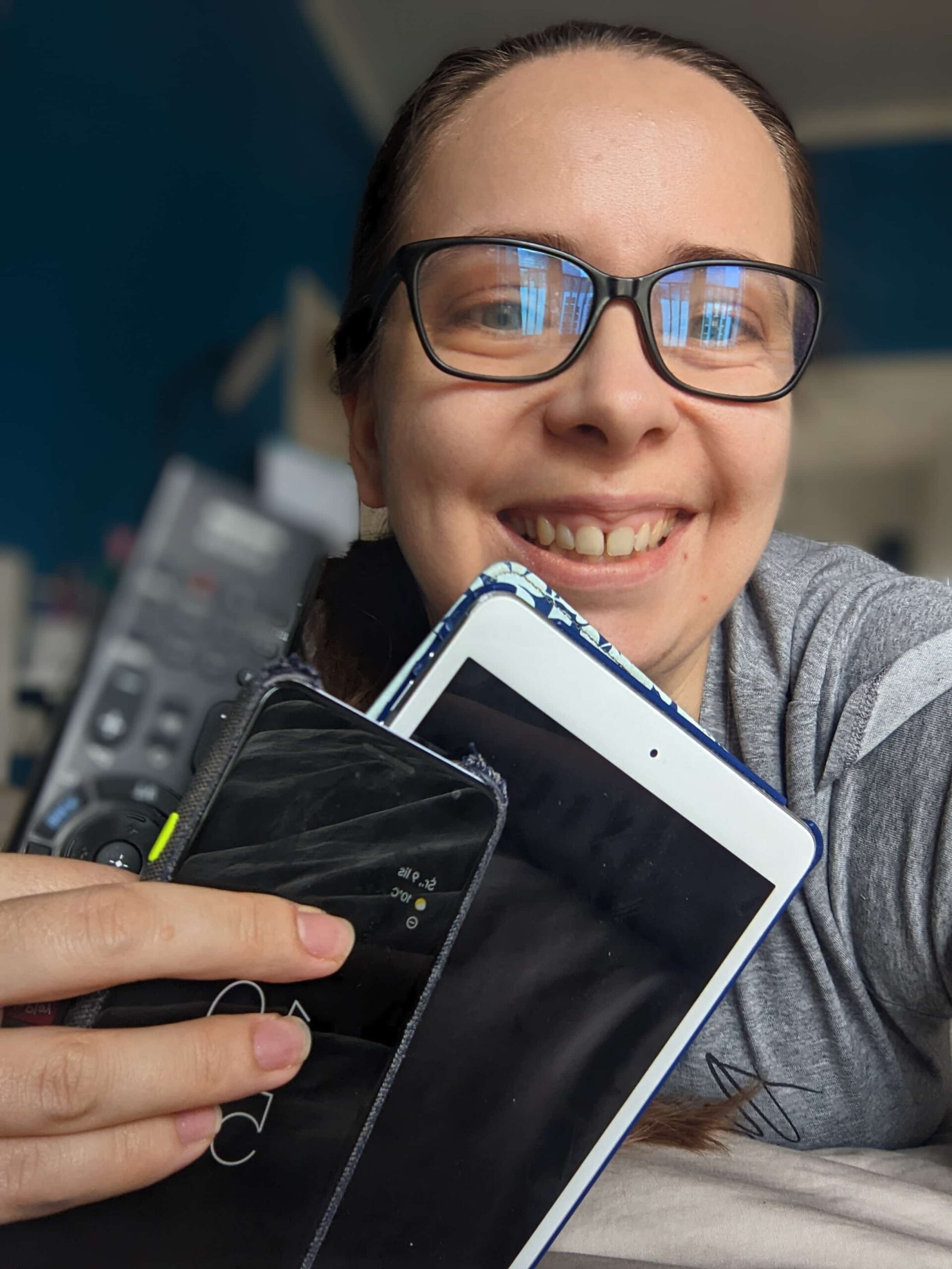 Beata Broniek, uśmiechnięta blogerka, trzymająca w ręku tablet, telefon i pilota; mama 4 dzieci, która pomoże Ci ogarnąć